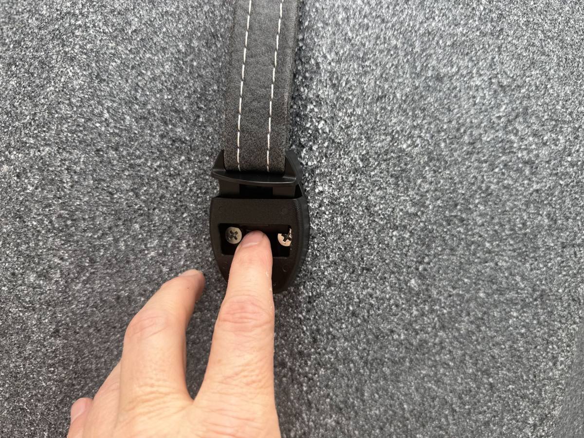 Pressing the center tab on a hot tub cover safety buckle to release it