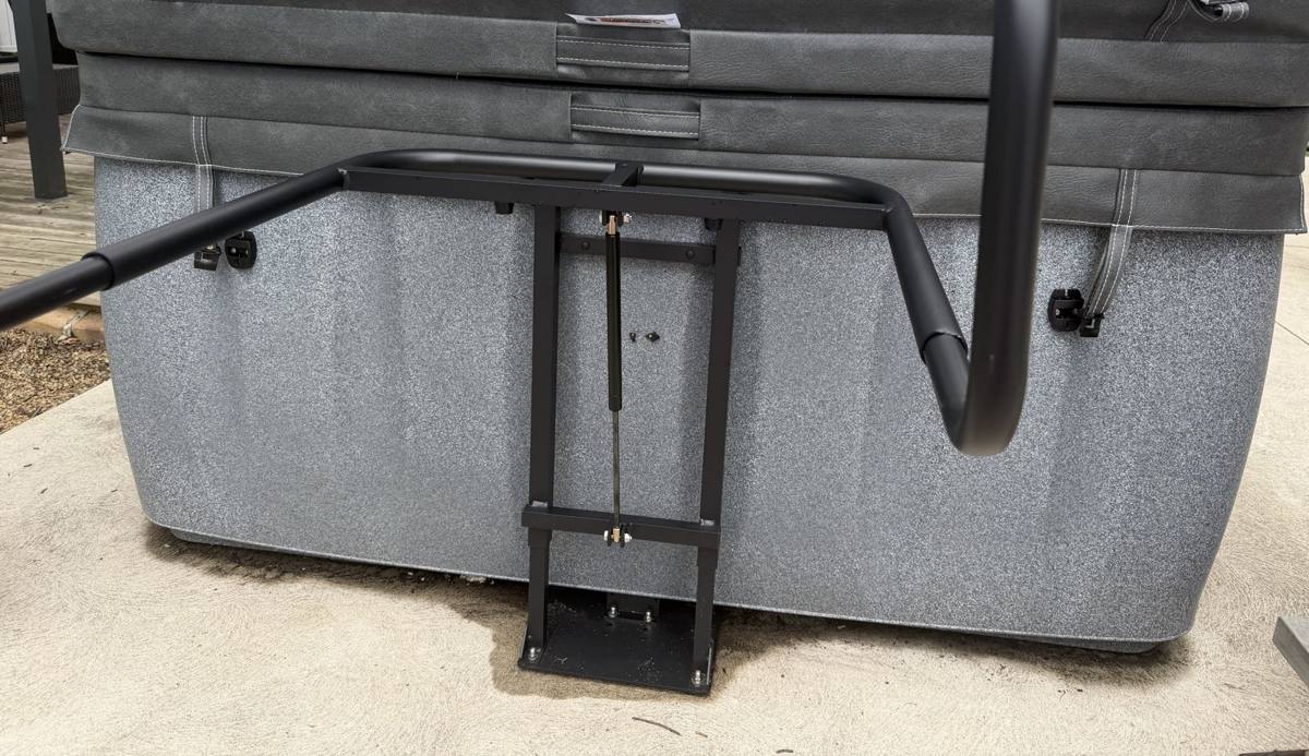 The black support bar behind the hot tub that holds the folded cover