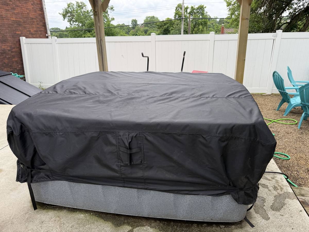 Thin black weather cover stretched over the closed hot tub