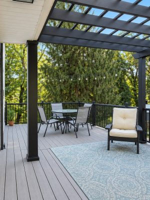 The covered deck under the pergola, with a table for outdoor meals and a lounge chair.